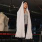 Person wearing a long white scarf in an indoor setting with mannequins in the background
