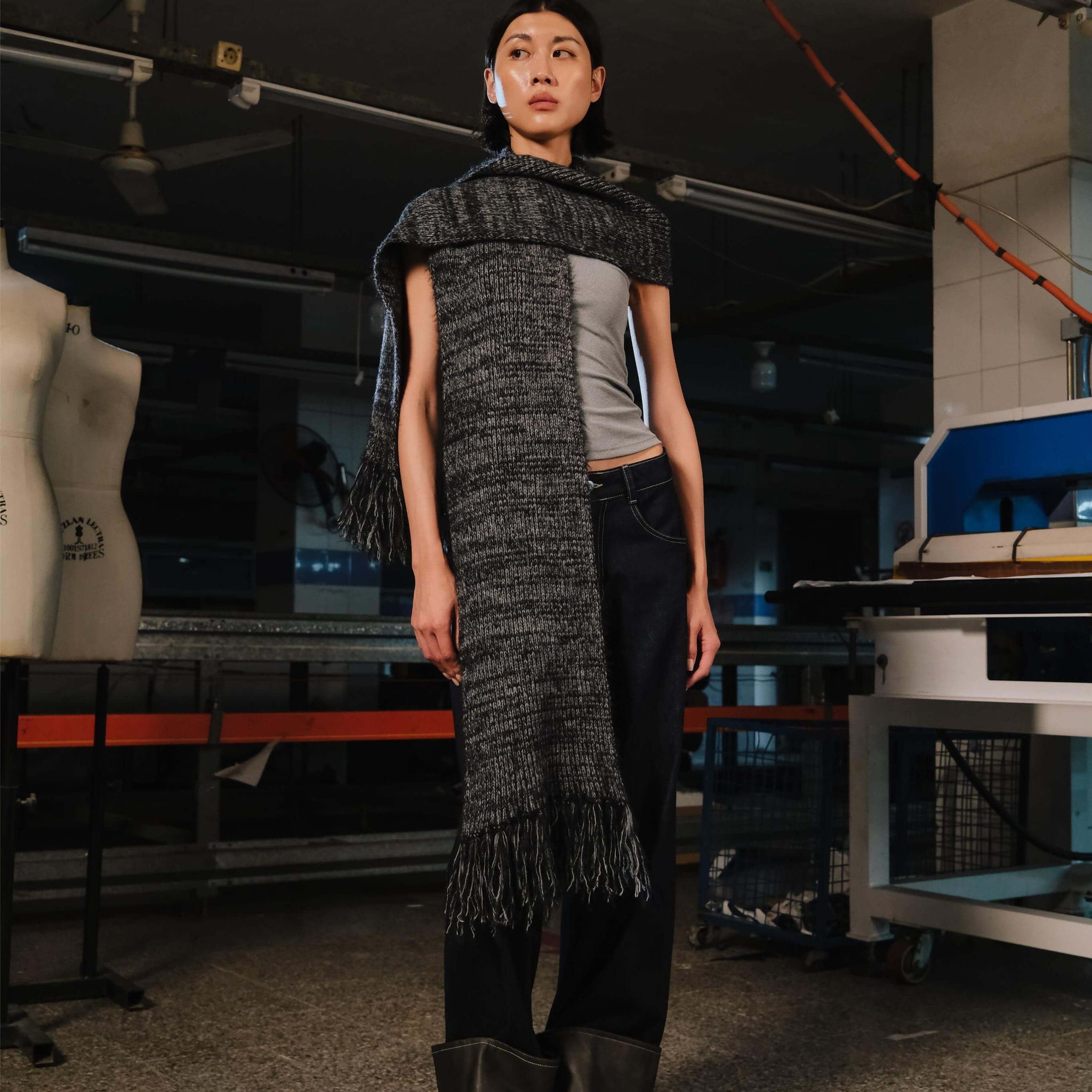 Person wearing a textured scarf and pants in an industrial setting