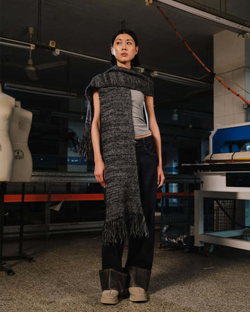 Person wearing a textured scarf and pants in an industrial setting