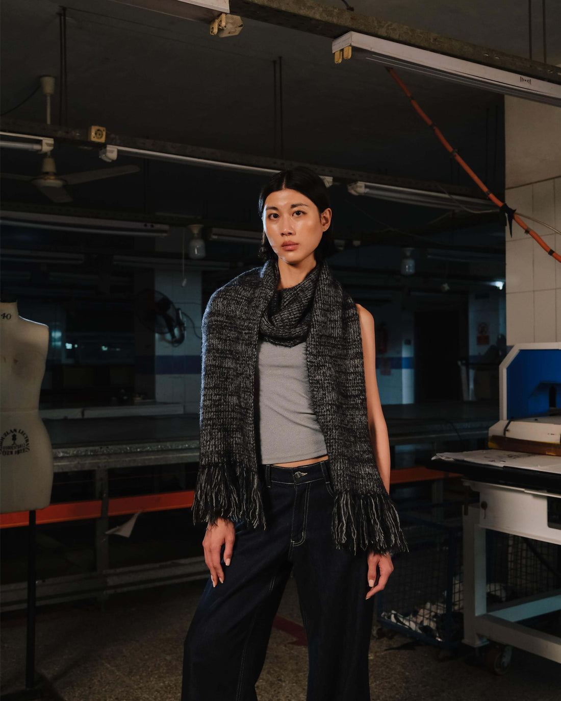 Person wearing a textured scarf and pants in an industrial setting