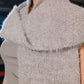 Close-up of a textured gray sleeveless garment with a blurred background