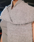 Close-up of a textured gray sleeveless garment with a blurred background