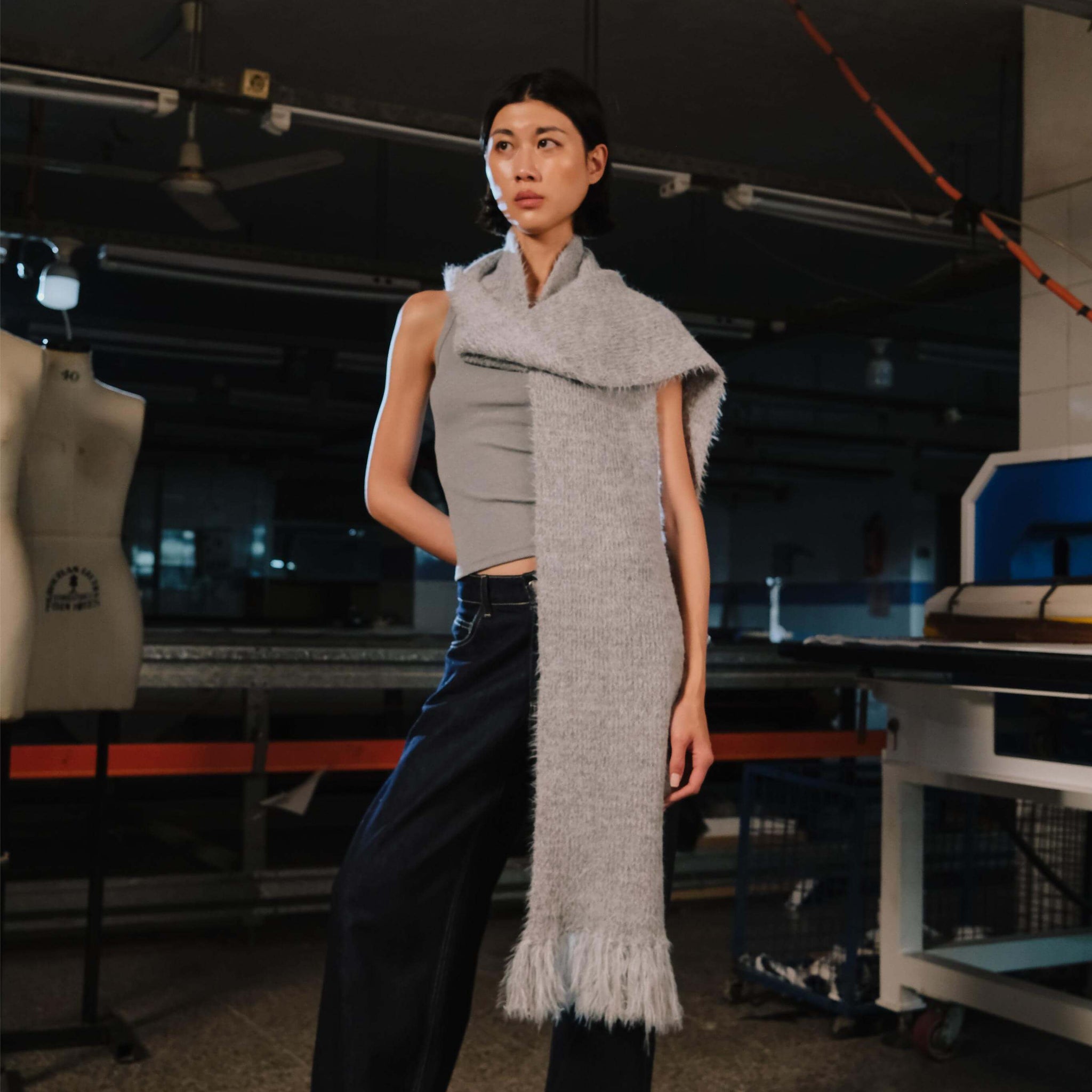 Person wearing a long gray scarf in an industrial setting