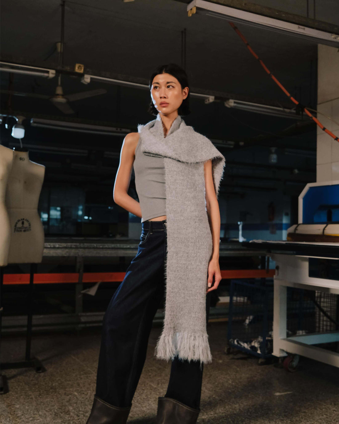 Person wearing a long gray scarf in an industrial setting