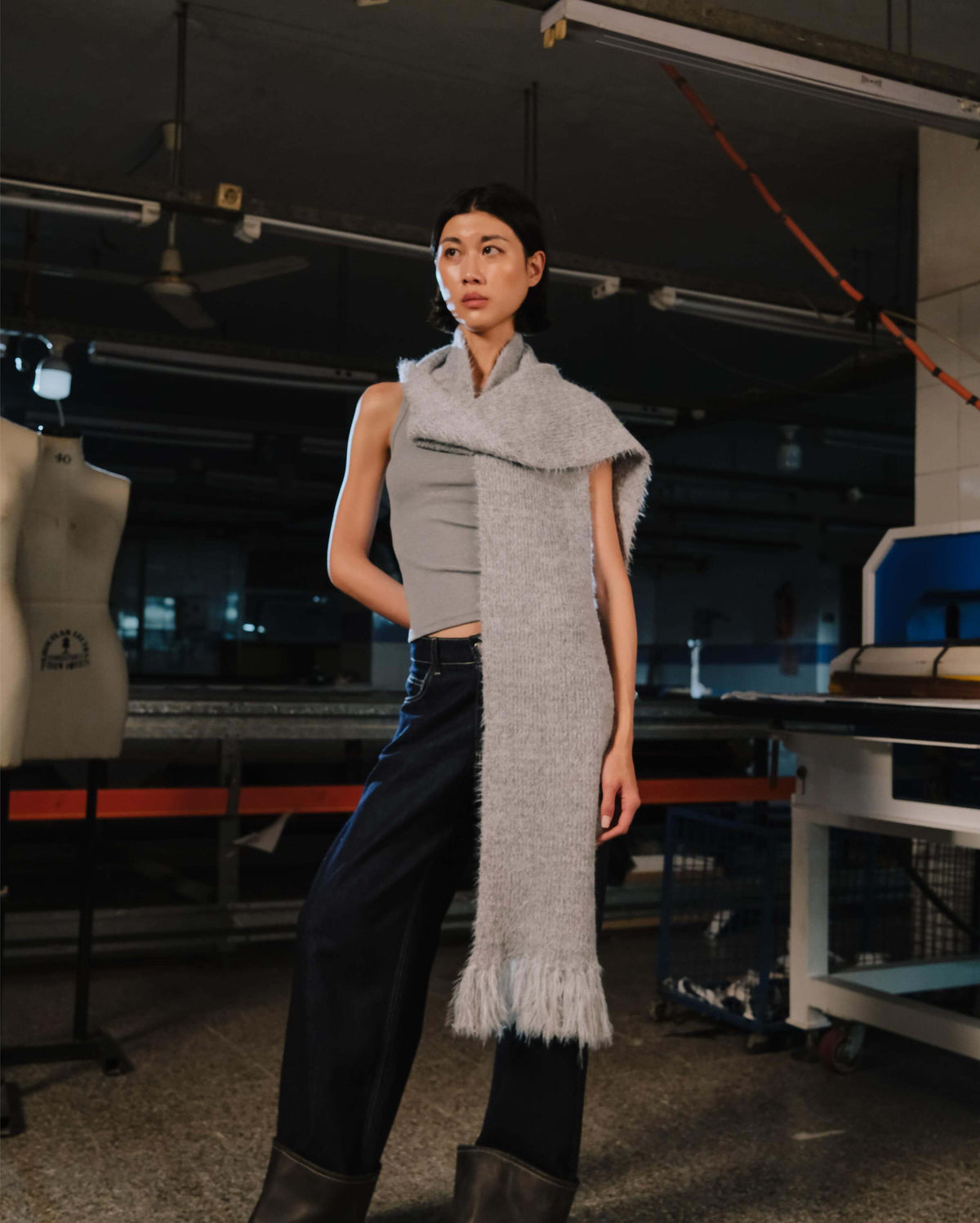 Person wearing a long gray scarf in an industrial setting