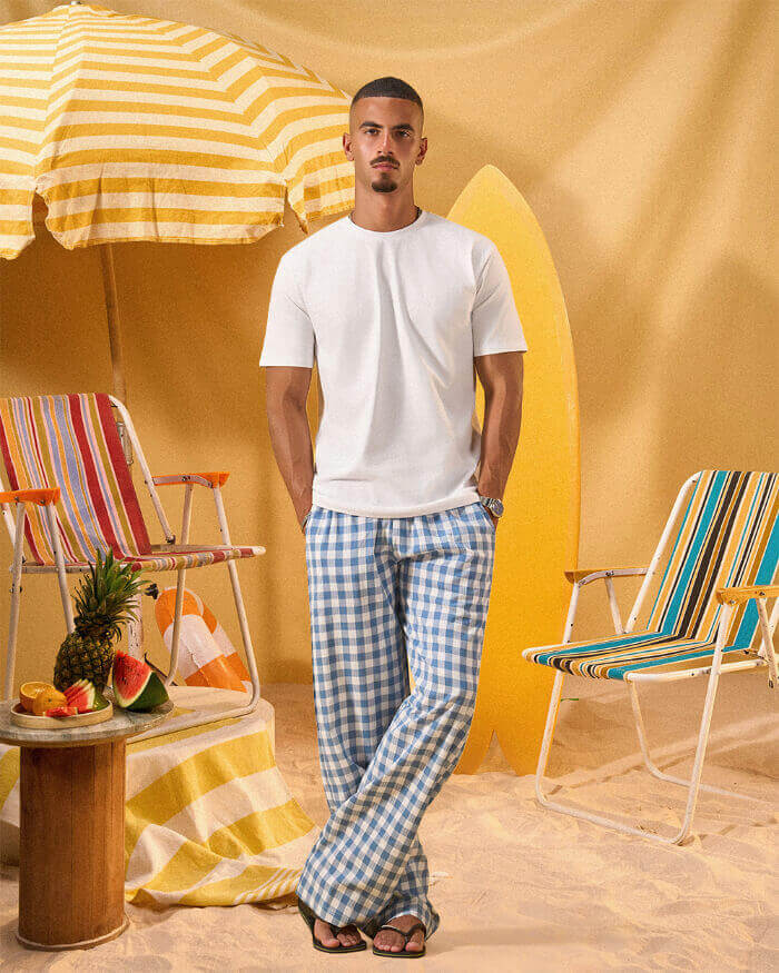 a man wearing a white tee and blue and white checkered lounge pants
