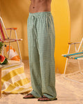 a man wearing a white tee and green and white checkered lounge pants