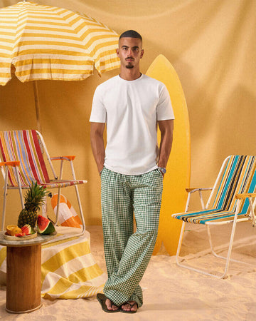 a man wearing a white tee and green and white checkered lounge pants
