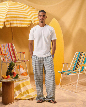 a man wearing a white tee and grey and white checkered lounge pants