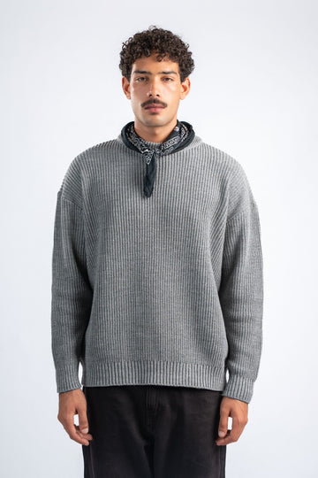 Man wearing a gray sweater with a black bandana around his neck on a white background