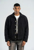 Man wearing a dark jacket over a white shirt on a plain background