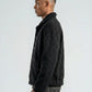 Man wearing a dark jacket and gray pants against a white background