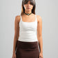 Woman wearing a white tank top and brown skirt on a gray background