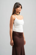 Woman wearing a white tank top and brown skirt on a gray background