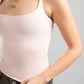 Person wearing a light pink tank top and gold necklace on a gray background