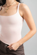 Person wearing a light pink tank top and gold necklace on a gray background