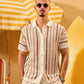 Man wearing a patterned shirt and sunglasses under a yellow and white striped umbrella.
