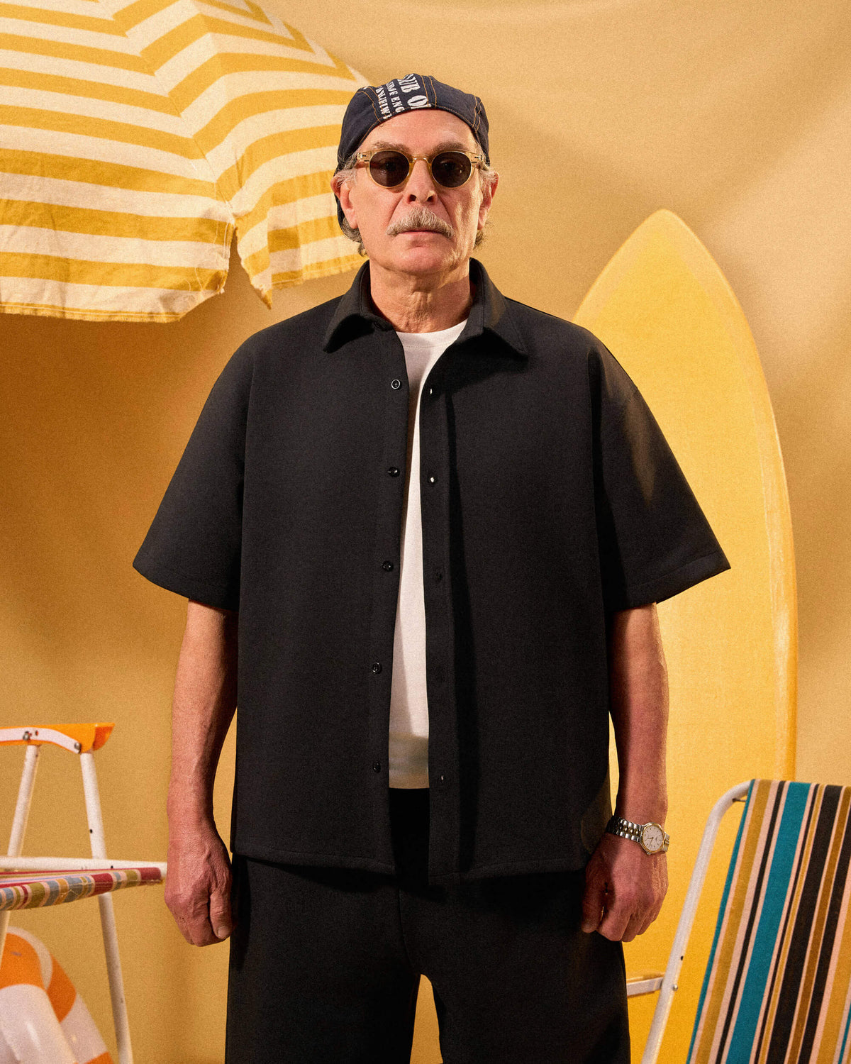 Man wearing sunglasses and a black shirt with a yellow background