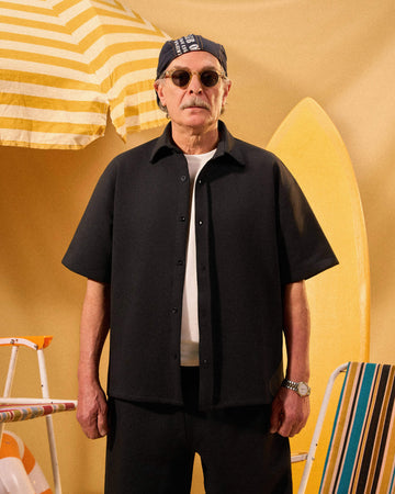 Man wearing sunglasses and a black shirt with a yellow background