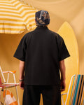 Person wearing a black shirt and cap with a yellow and white striped umbrella in the background