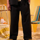 Person wearing black pants standing in a room with yellow walls and colorful chairs.