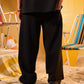 Person wearing black pants standing on a sandy surface with beach chairs in the background.