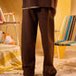 Person wearing brown pants standing in a room with yellow walls and colorful chairs.