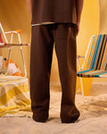 Person wearing brown pants standing in a room with yellow walls and colorful chairs.
