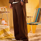 Person wearing a brown suit with a yellow background and vintage chairs.