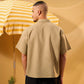 Man wearing a beige shirt standing next to a yellow and white striped umbrella on a yellow background