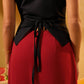 Person wearing a black top and red pants with a blurred background