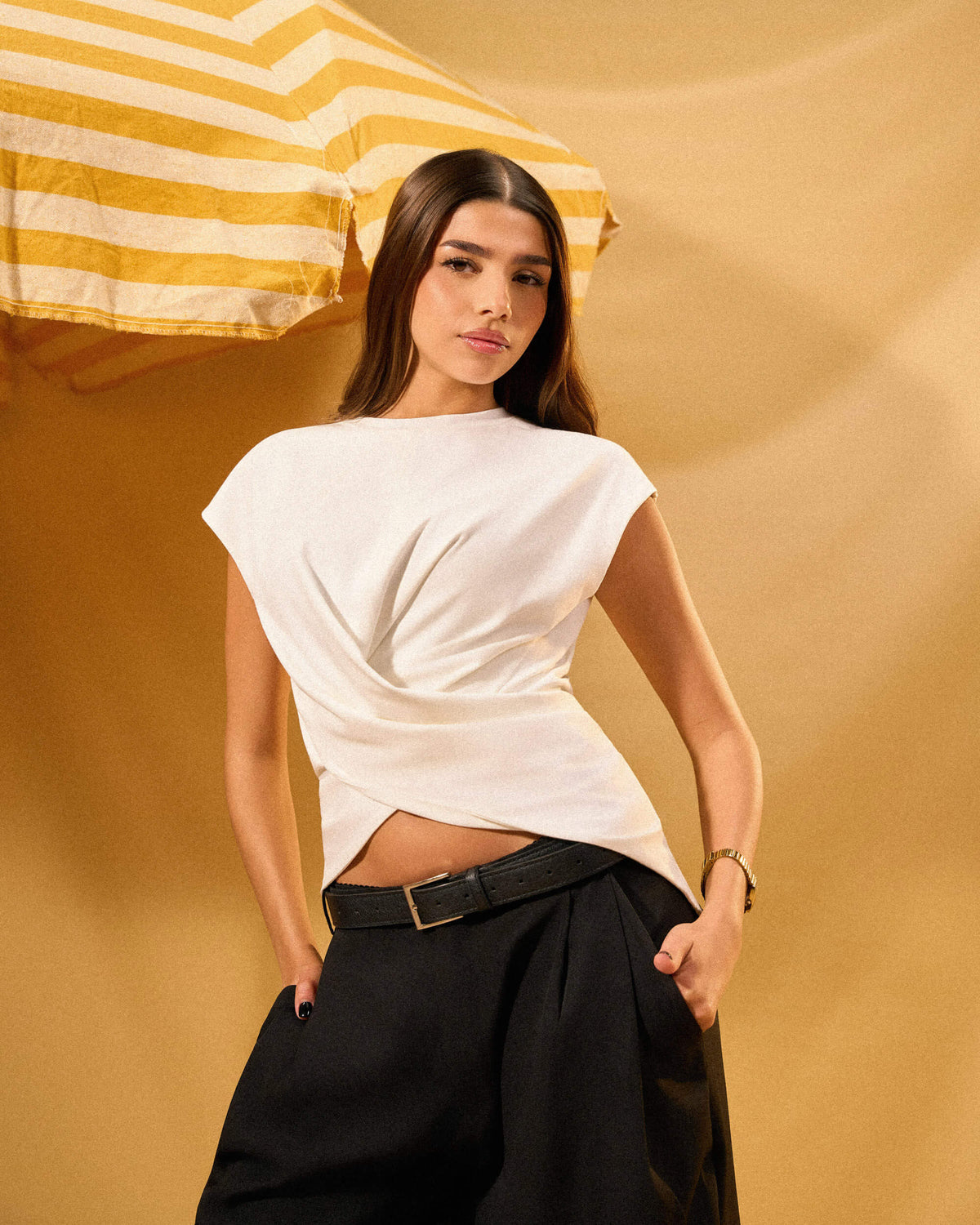 Woman wearing a white top and black pants against a yellow background