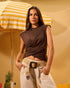 Woman in a brown top and beige pants standing under a yellow and white striped umbrella with a pineapple and watermelon on a yellow background.