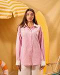 Woman wearing a pink striped shirt against a yellow background with beach elements.