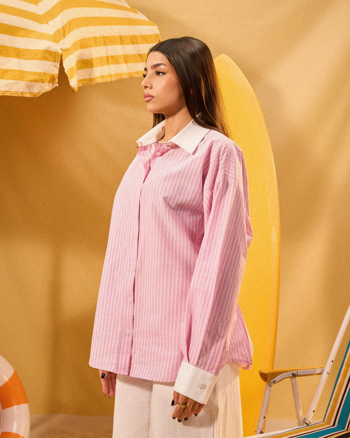 Woman wearing a pink striped shirt against a yellow background