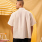 Man wearing a beige shirt standing in front of a yellow and white striped umbrella.