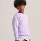 A child model wearing a light purple crewneck sweatshirt, a white undershirt, and blue jeans, photographed against a neutral light gray studio background.