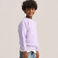 A child model wearing a light purple crewneck sweatshirt, blue jeans, and white sneakers, standing against a solid light gray studio background.