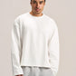 a man wearing a white long sleeves boxy t-shirt on an ash grey sweatpants with a solid background