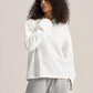 a woman wearing a white long sleeves boxy t-shirt on a ash-grey sweatpants with a solid background