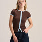 A woman modeling a brown short-sleeve ribbed top with light blue trim details, paired with dark blue jeans, against a plain light beige studio background.