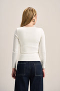 A woman shown from the back wearing a fitted off-white long-sleeve top and dark blue jeans against a plain light beige studio background.