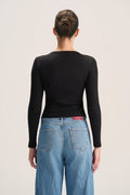 A woman shown from the back wearing a fitted black long-sleeve top and light blue jeans against a plain light background.