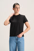 A woman modeling a black short-sleeve crewneck t-shirt paired with light blue jeans, standing against a plain light beige studio background.