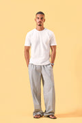a man wearing a white tee and grey and white checkered lounge pants