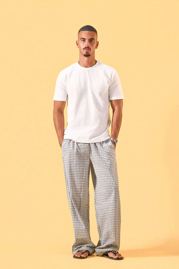 a man wearing a white tee and grey and white checkered lounge pants