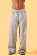 a man wearing a white tee and grey and white checkered lounge pants