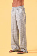 a man wearing a white tee and grey and white checkered lounge pants