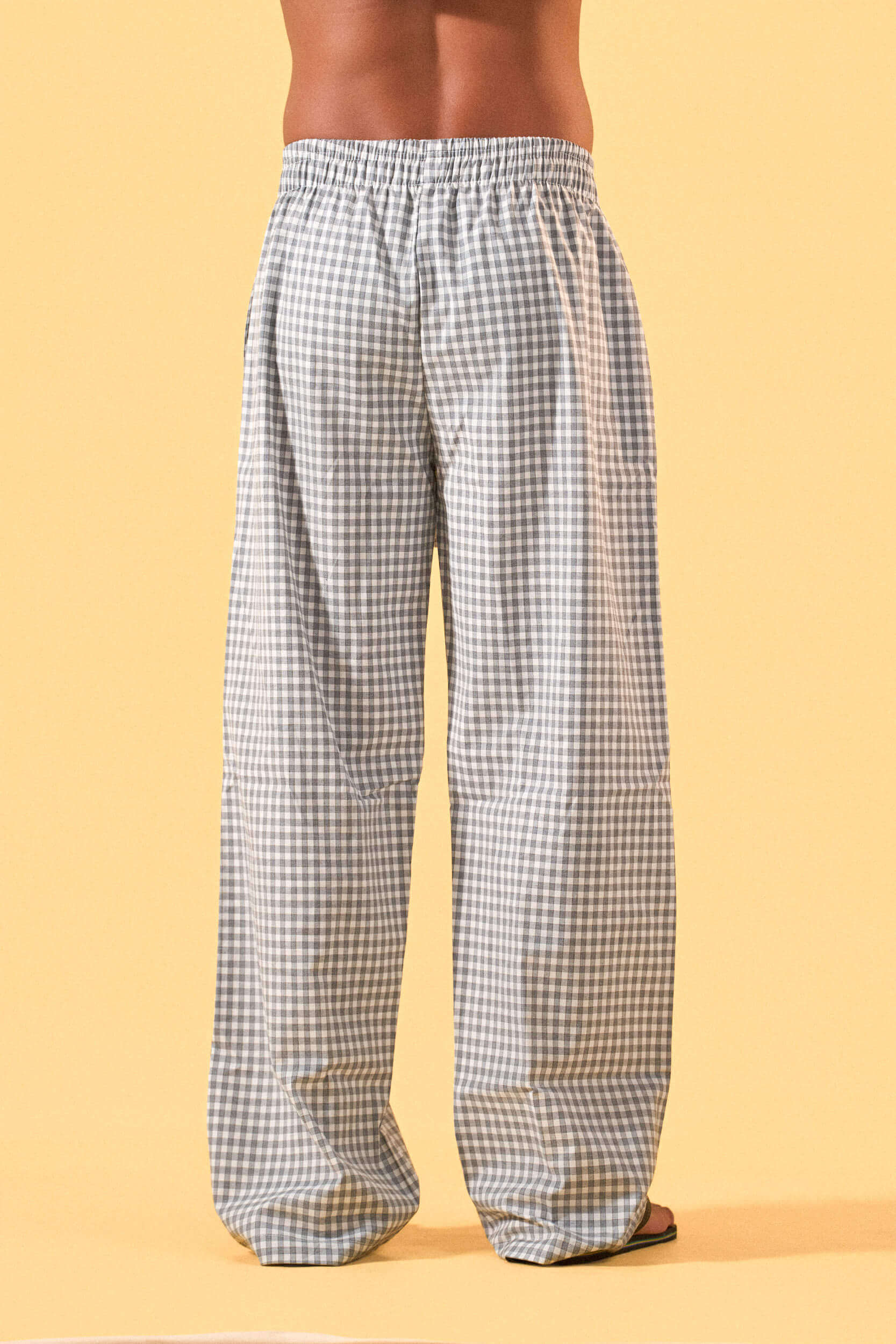 a man wearing a white tee and grey and white checkered lounge pants