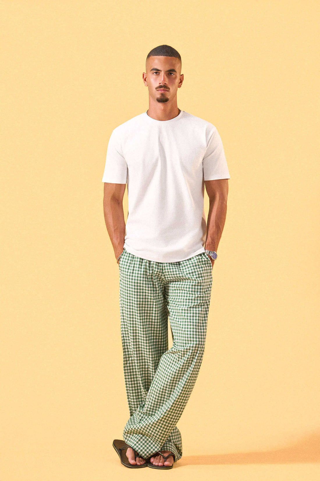 a man wearing a white tee and green and white checkered lounge pants